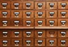 Close-up of a vintage wooden card catalog with numerous drawers and metal handles.