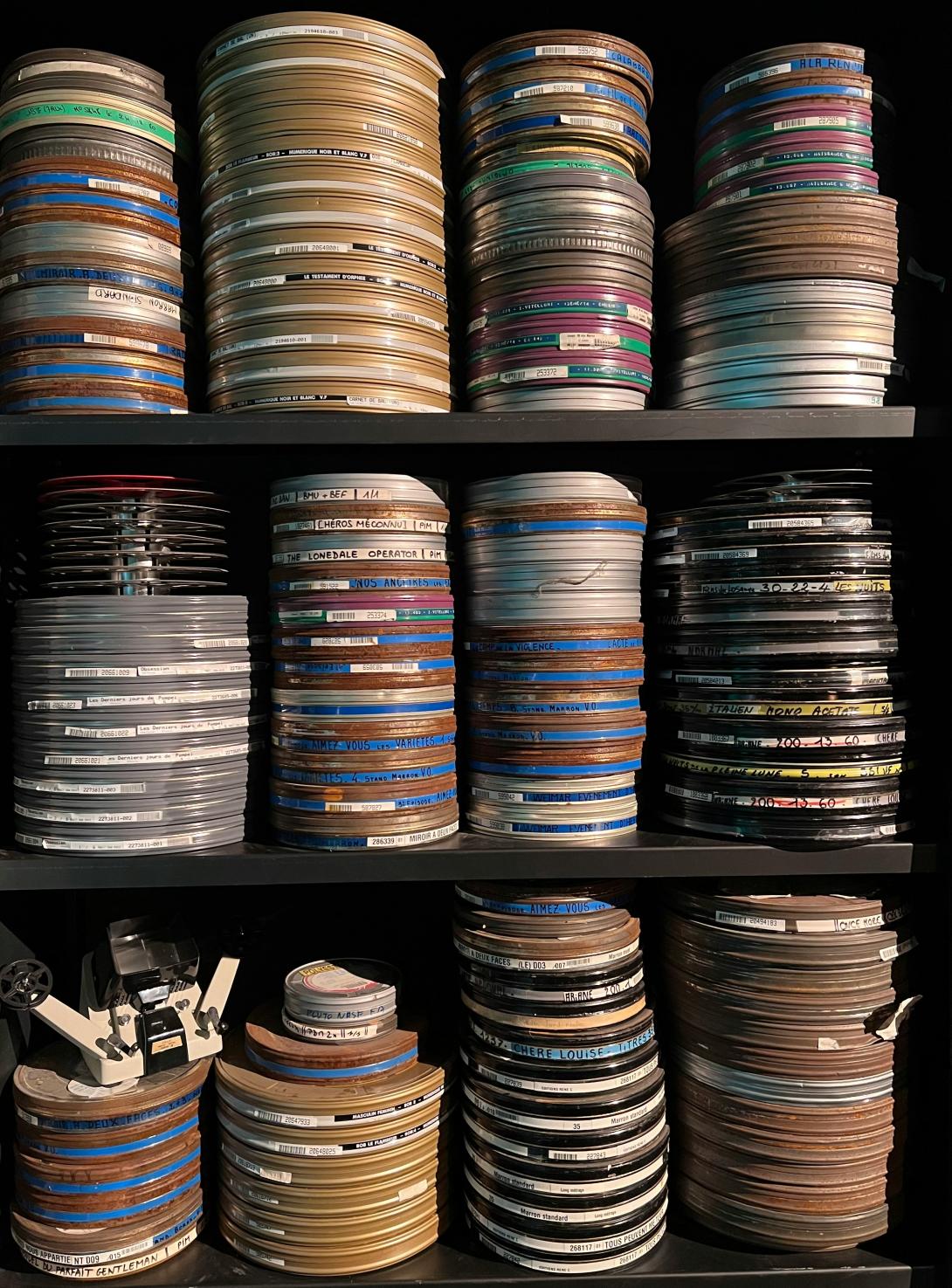 Shelves stacked with numerous reels of film or magnetic tape, suggesting a large collection of media assets. The reels vary in size and have labels, hinting at archived content.