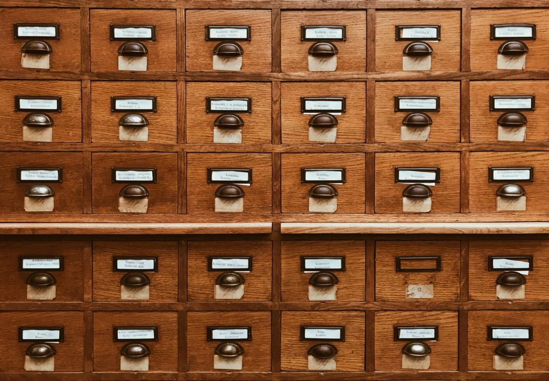 Close-up of a vintage wooden card catalog with numerous drawers and metal handles.