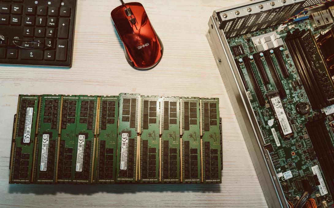 A close-up shot of a motherboard, RAM modules, and server internals on a workbench—evoking hands-on technical work and system architecture. Photo by Yuriy Vertikov via Unsplash